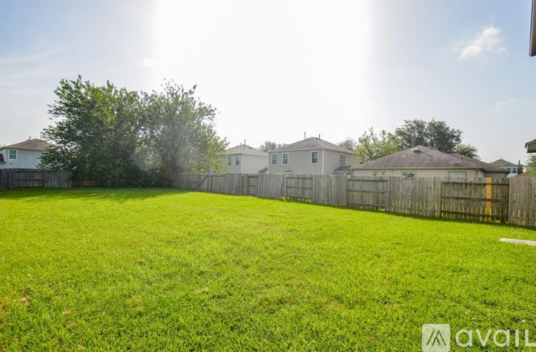 A sunny day in a backyard with a fence and houses in the background.