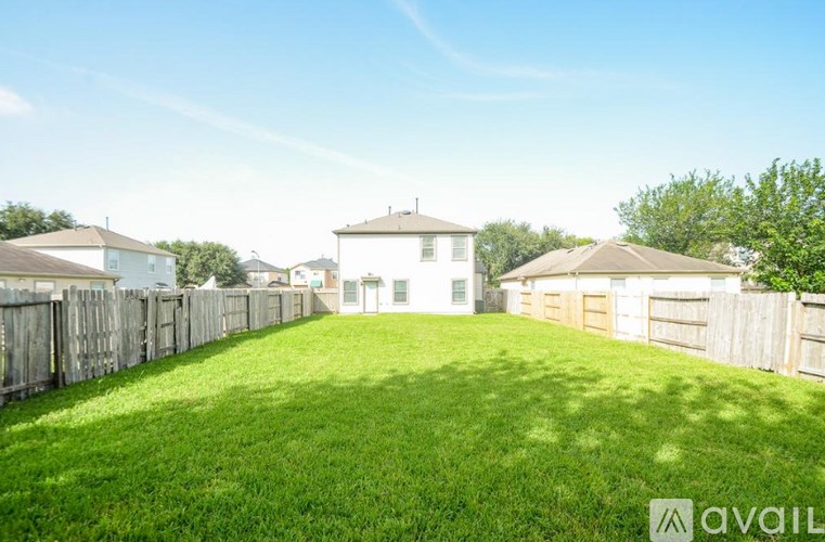 A grassy backyard with a fence and houses in the background.