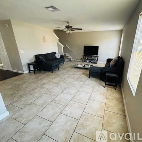 A living room with a black couch and a television.