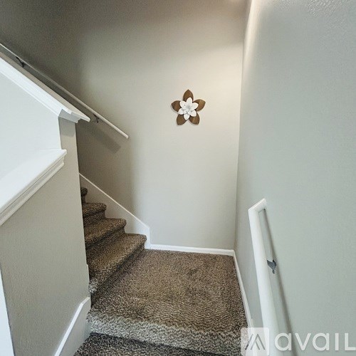 A staircase with a carpeted runner and a flower decoration on the wall.
