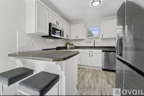 A kitchen with white cabinets and a granite countertop.