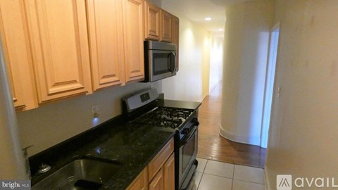 A kitchen with wooden cabinets and black countertops.