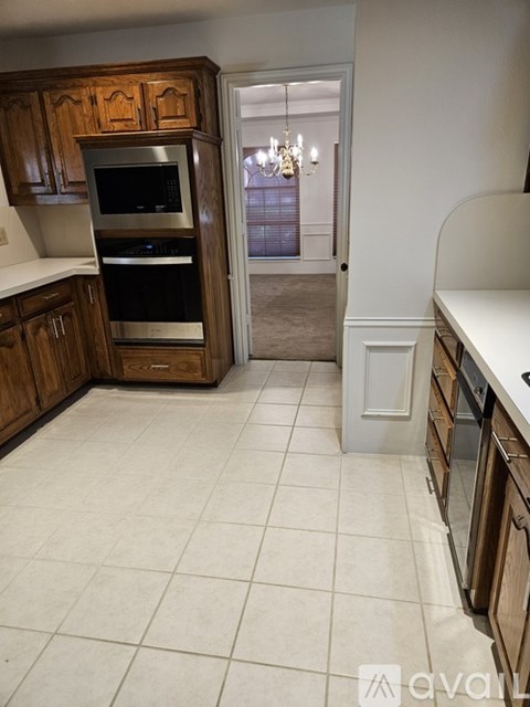 A kitchen with wooden cabinets and a white tiled floor.