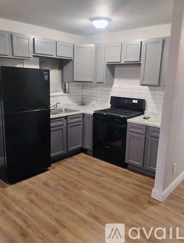 A kitchen with black appliances and wooden floors.