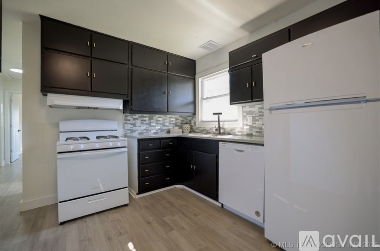 A kitchen with black cabinets and white appliances.