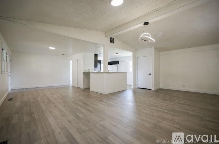 A spacious room with wooden flooring and white walls.