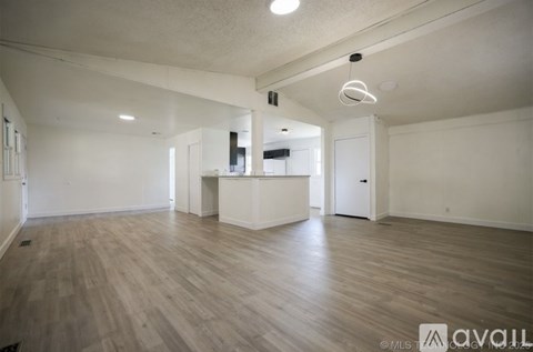 A spacious room with wooden flooring and white walls.