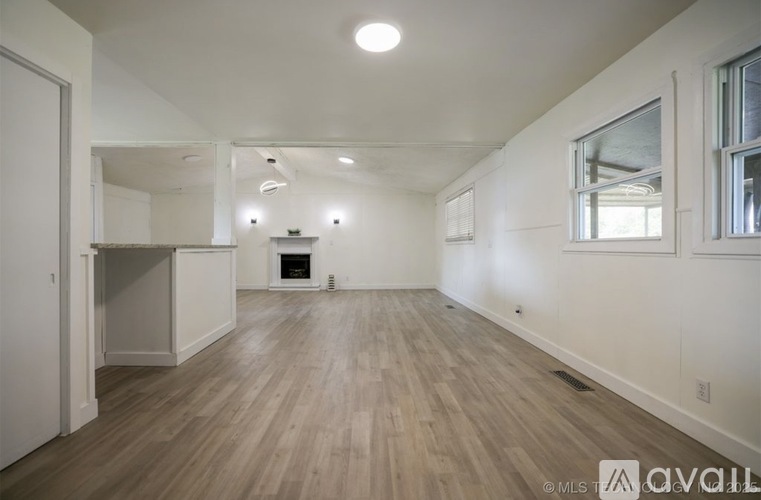 A spacious room with wooden flooring and white walls.