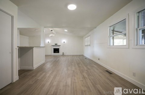 A spacious room with wooden flooring and white walls.