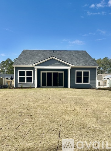 A grey house with a black roof and a white garage door.