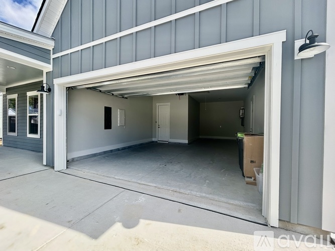A garage with a white door is open and a cardboard box is visible inside.