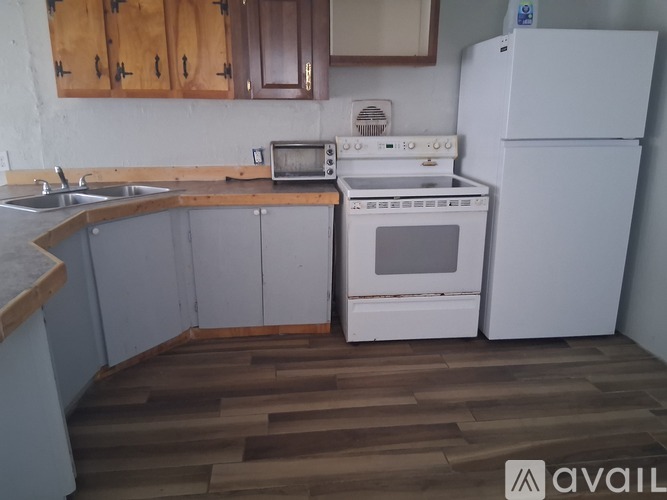 A kitchen with a white oven and microwave, a sink, and wooden cabinets.