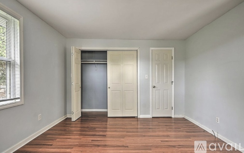 A room with a wooden floor and two doors, one of which is open.