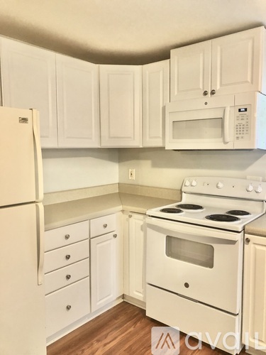 A white kitchen with a stove, refrigerator, and cabinets.