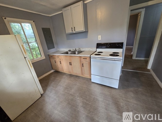 A kitchen with a white refrigerator, stove, and cabinets.