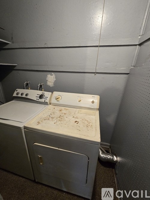 A dirty old stove top oven sits in a room with grey walls.
