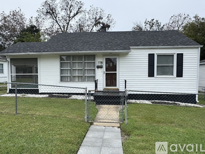 A white house with a black roof and a fence surrounding it.