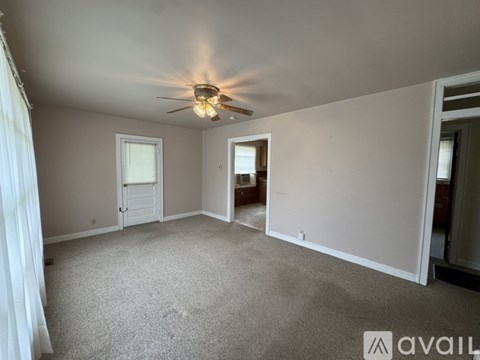 A spacious room with a ceiling fan and carpeted floor.