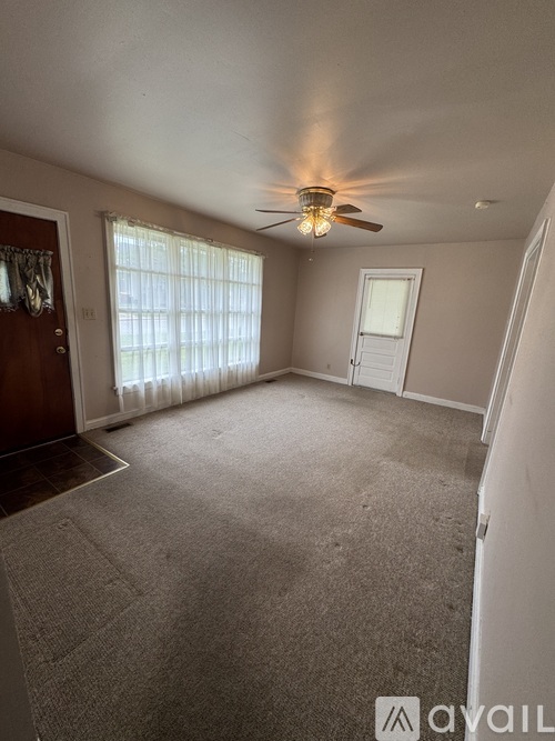 A room with a ceiling fan and carpeted floor.