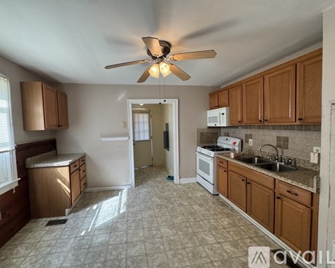 A kitchen with a fan and a refrigerator.