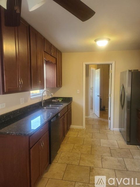 A kitchen with brown cabinets and black countertops.