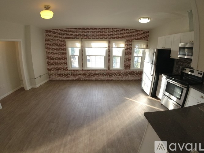 A kitchen with a brick wall and wooden flooring.