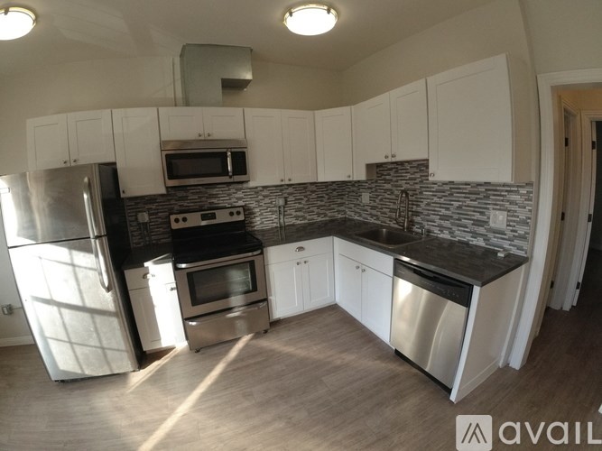 A kitchen with white cabinets and a stone backsplash.
