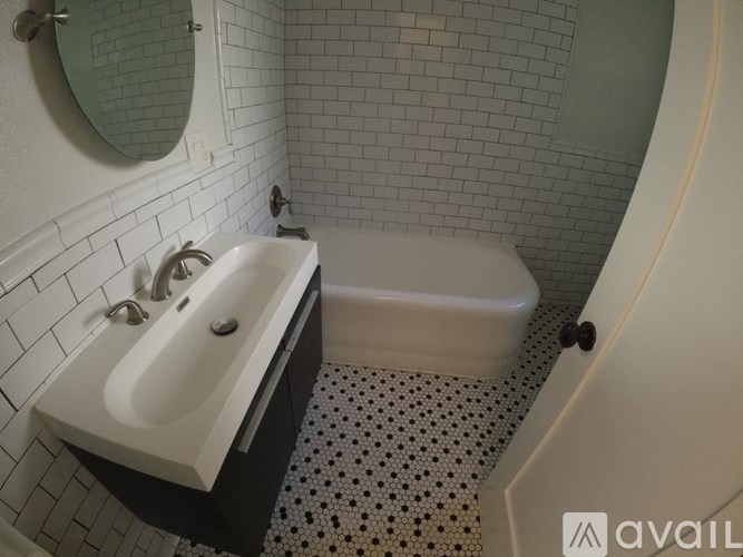 A white sink with a black counter top and a white tub in a bathroom.