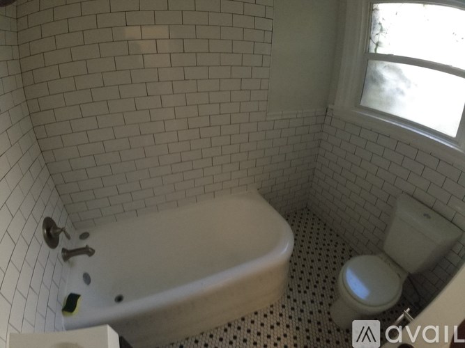 A white bathroom with a tub, toilet and window.