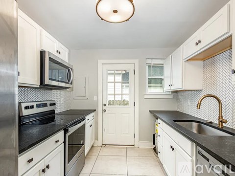 A kitchen with white cabinets and black countertops.
