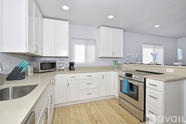 A kitchen with white cabinets and wooden floors.