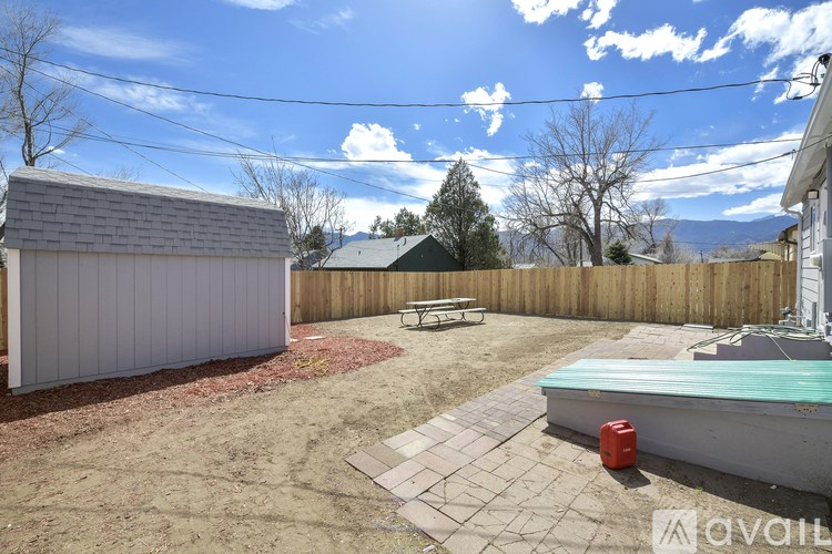 A backyard with a shed, bench, and a pool table.