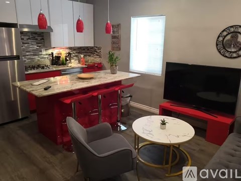 A modern kitchen with red accents and a TV in the corner.