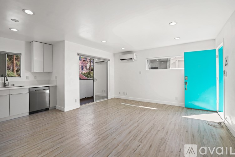 A spacious, empty room with wooden floors and white walls.
