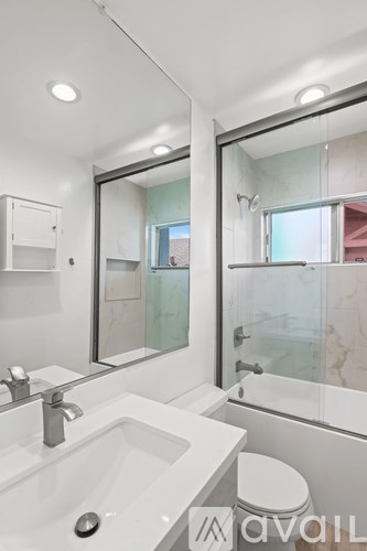 A modern bathroom with a sink, toilet, and a large mirror.