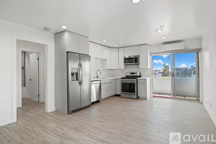 A modern kitchen with stainless steel appliances and wooden flooring.
