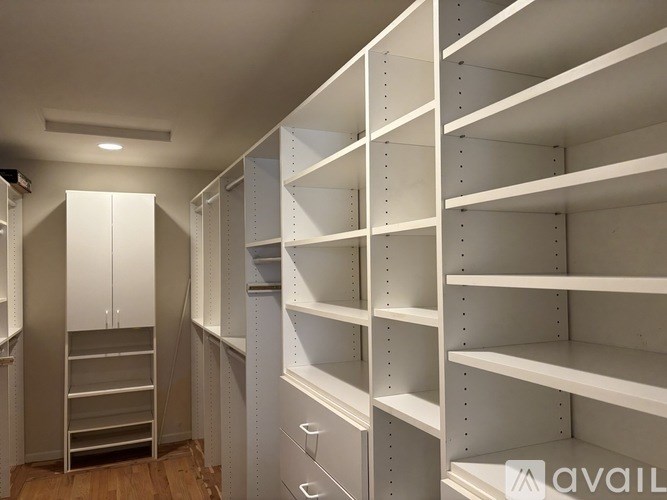 A white walk-in closet with shelves and drawers.