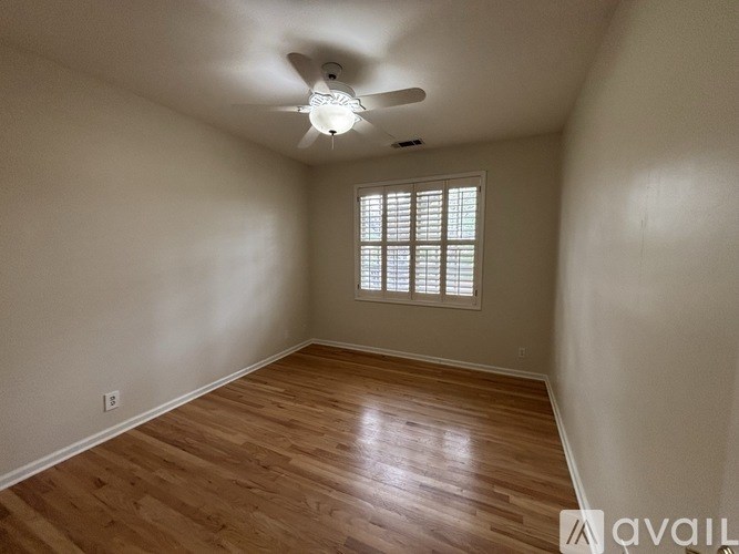 A room with wooden flooring and a window with blinds.