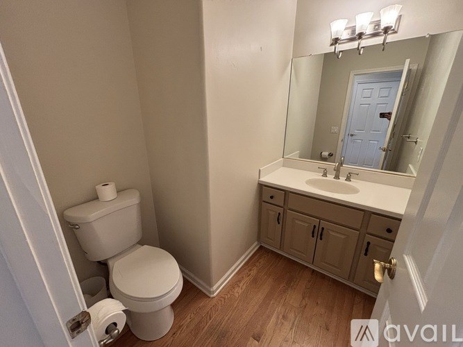 A bathroom with a toilet, sink, and mirror.