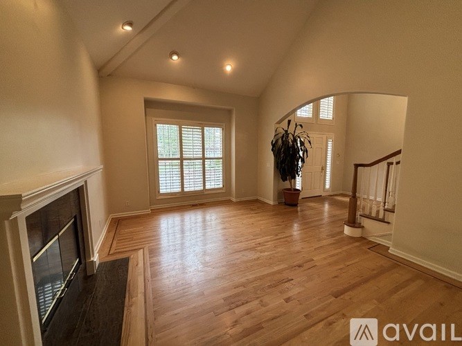 A spacious living room with wood flooring and a fireplace.