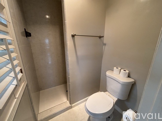 A white toilet with a toilet paper holder and a glass shower stall with a door.
