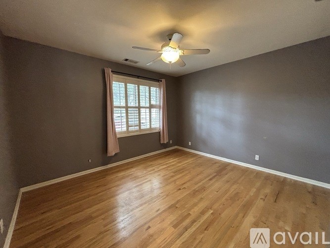 A room with wooden flooring and a ceiling fan.