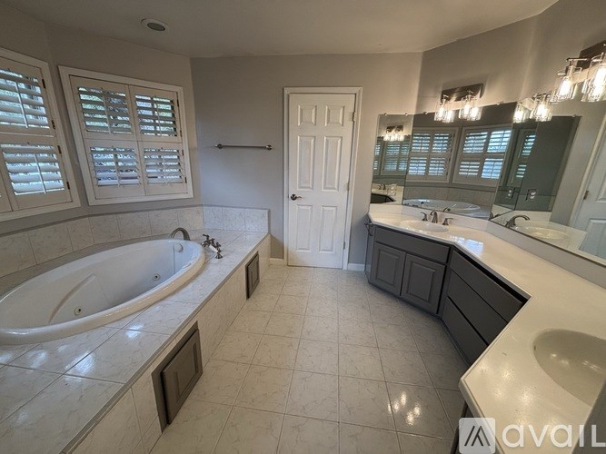 A bathroom with a tub, sink, and mirror.
