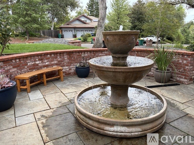 A stone fountain is in the middle of a patio.