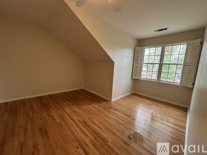 A room with wooden flooring and a window with blinds.