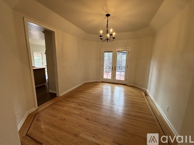 A room with wooden floors and a chandelier hanging from the ceiling.