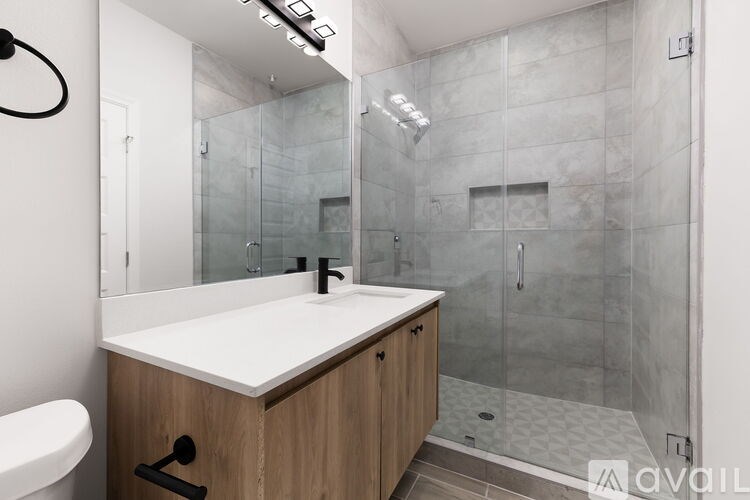 A modern bathroom with a walk-in shower and a white sink.