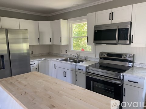 A kitchen with white cabinets and a wooden countertop.