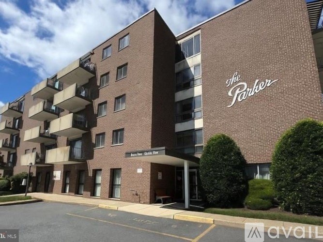 The Parker apartment building is a multi-story brick building with a parking lot in front.