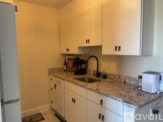 A kitchen with white cabinets and granite countertops.